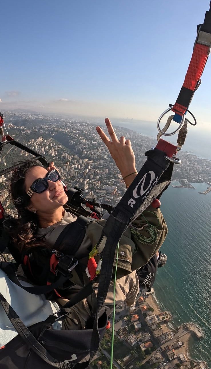 Passenger flashing a peace sign while paragliding above Jounieh Bay