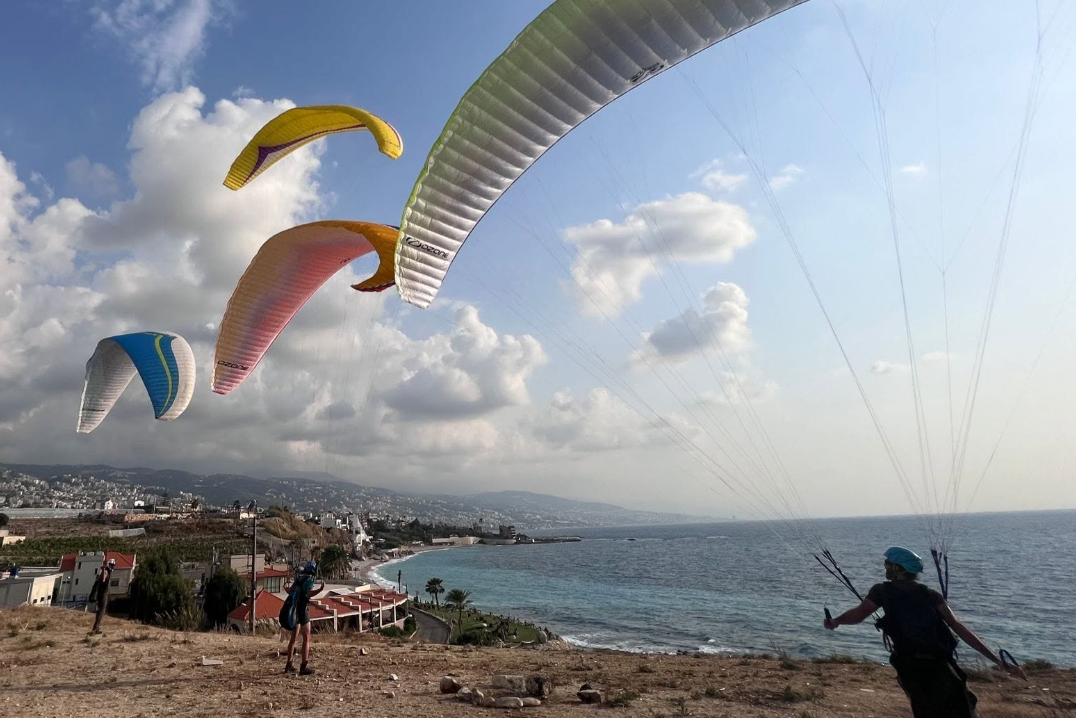 Multiple paragliders flying over the Lebanese coastline near Jounieh
