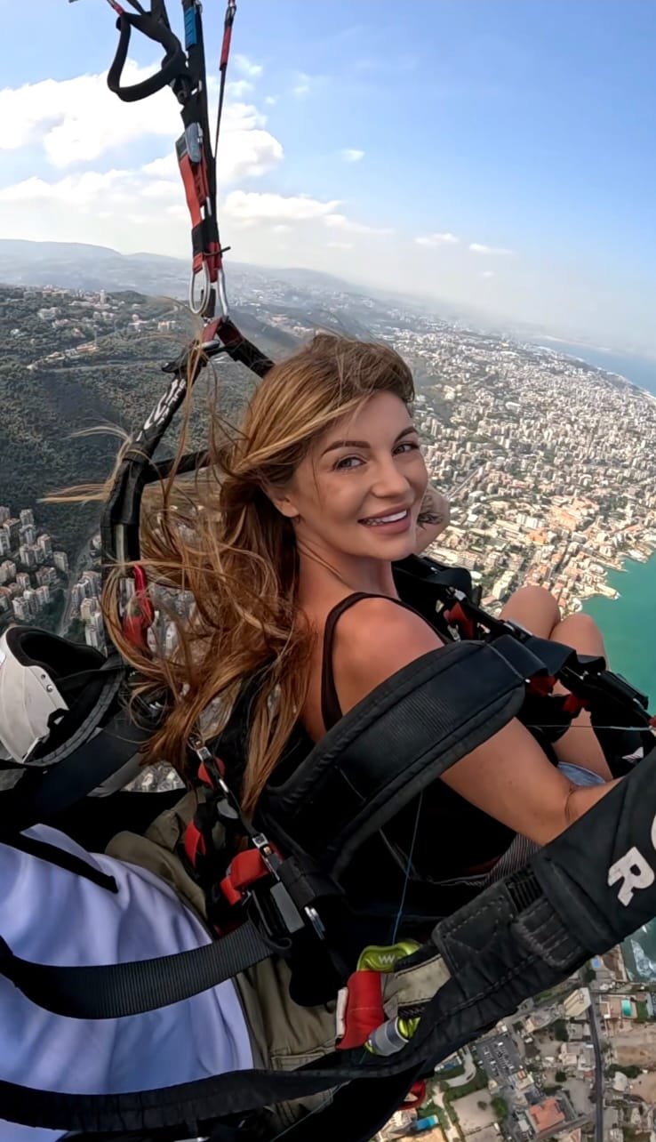 Happy passenger paragliding over Jounieh with the bay in the background