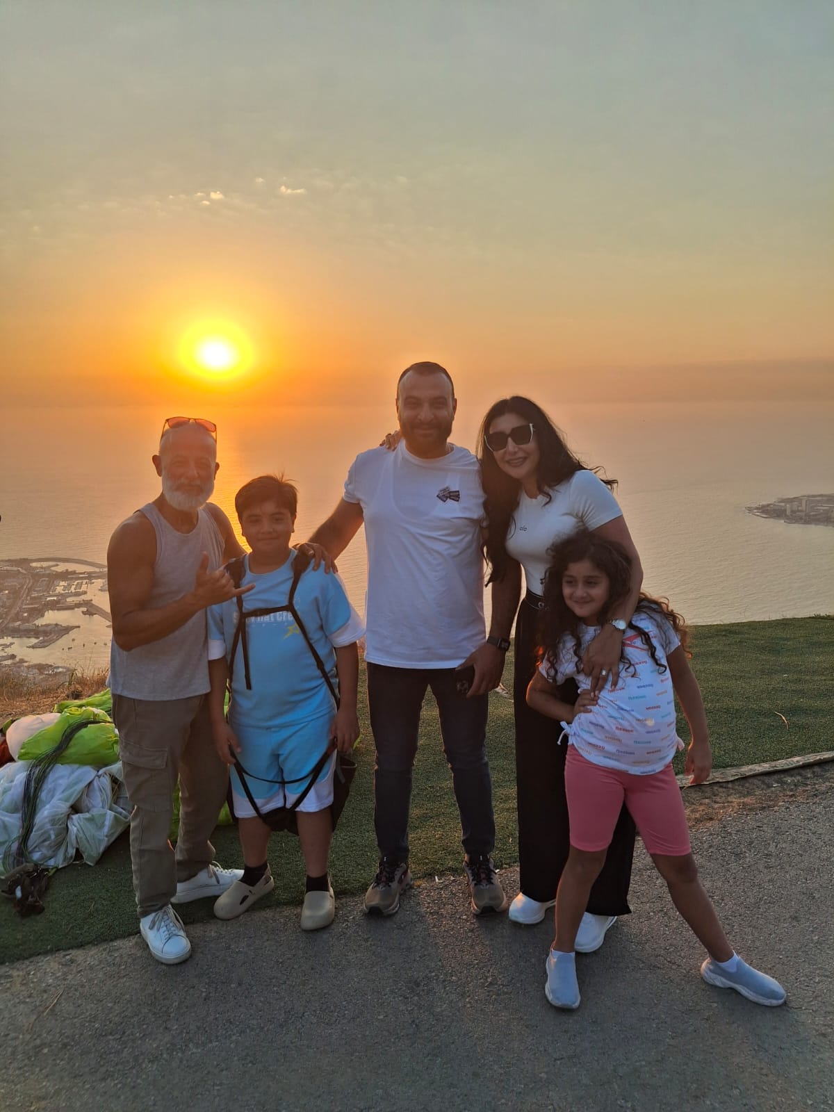 Family posing at the Ghosta launch site at sunset before a paragliding flight